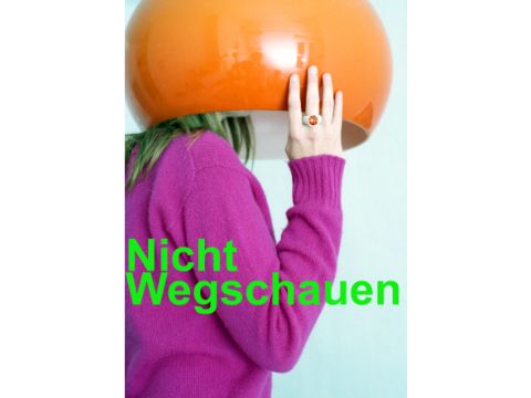 Eine Frau im pinken Pullover hällt einen runden orangenen Glaslampenschirm über ihren Kopf
