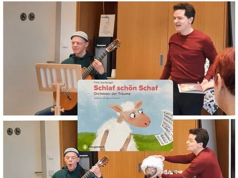 Ein Mann spielt Gitarre daneben aggiert ein Man mit einem Schaf in der Hand