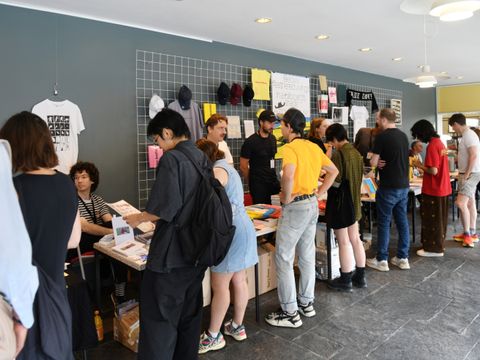 Menschen stehen um Tische und eine Ausstellung herum