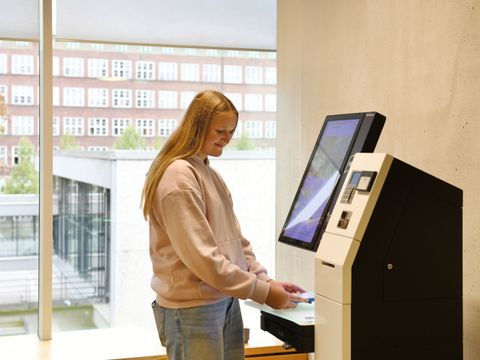 Mädchen leiht sich ein Medium am Automaten der Schiller-Bibliothek aus