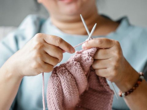 Eine Frau strickt an einem Textilprojekt