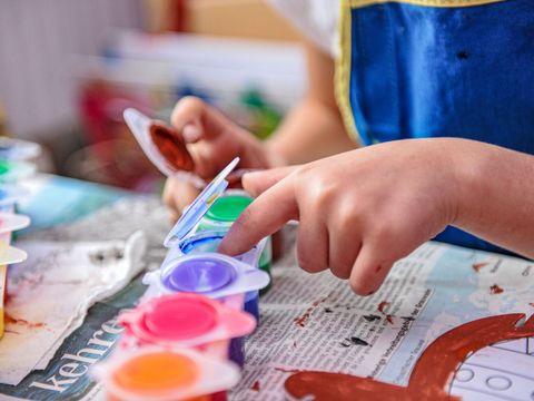 Kinderhände fassen in bunter Farbe