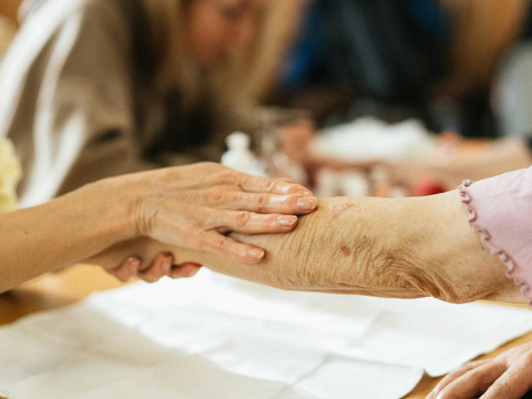 Eine jüngere Frau hält die Hand einer älteren Dame