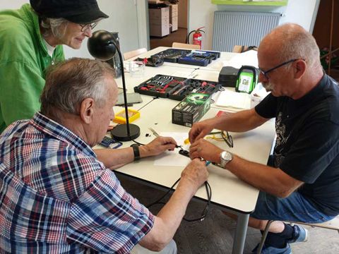 Menschen basteln beim Repaircafé an technischen Geräten