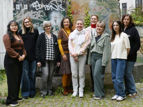 Neun Bibliotheksmitarbeitende stehen im Hof der Bibliothek und lächeln freundlich.
