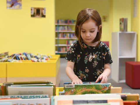 Kind in Vorschulalter stöbert im Kindbereich der Janusz-Korczak-Bibliothek.