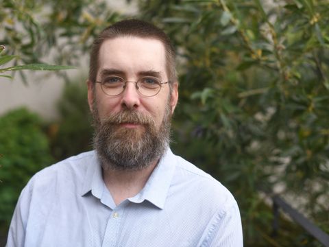 Bibliotheksleitung Herr Weiß: mitte 30, lächelt, hat Bart und Brille.