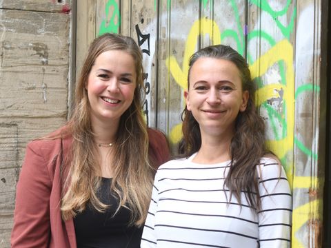 Die Leitung und stellvertretende Leitung vor der Bibliothek. Sie lächeln freundlich.
