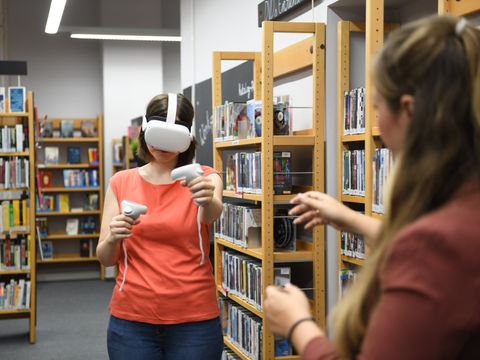 VR-Brille: Eine Frau in der Bibliothek spielt mit Virtual Reality.