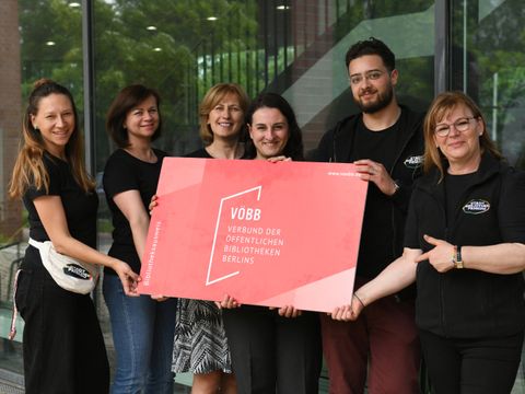 Das Team aus der Stadtteilbibliothek Karow mit einem großen Bibliotheksausweis