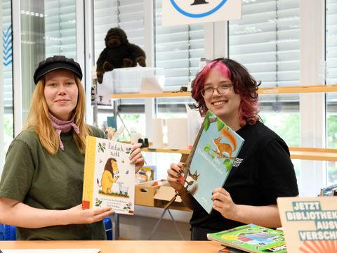 Zwei Bibliotheksmitarbeitende stellen Bücher vor