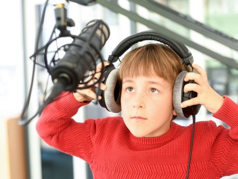 Kind in einem professionellen Tonstudio mit Kopfhörer und Mikrofon