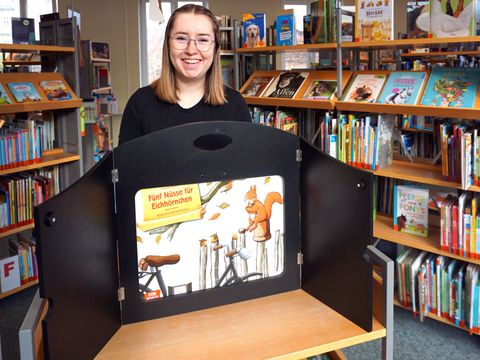 Kamishibai: Erzähltheater mit Tisch als Bühne. Eine Bibliotheksmitarbeiterin erzählt.