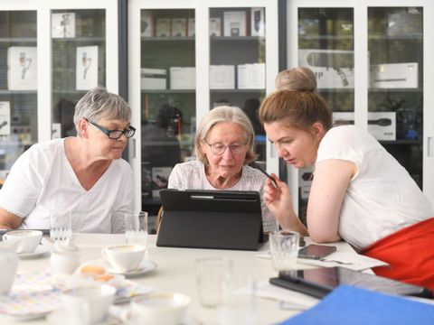 Eine Kollegin hilft zwei älteren Nutzerinnen mit Fragen rund um Internet und digitalen Diensten