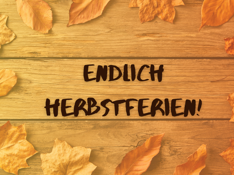 Im Hintergrund sind bunte Herbstblätter auf einer hölzernen Unterlage zu sehen. Im Vordergrund steht "Endlich Herbstferien!"
