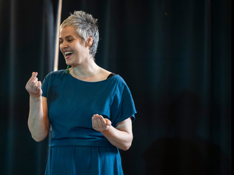 Kathleen Rappolt trägt ein blaues Kleid und erzählt lebhaft