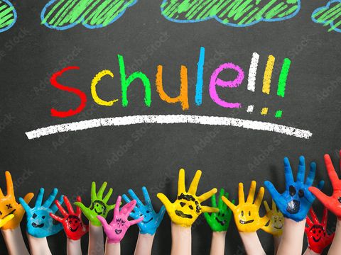 Bunt bemalte Hände vor schwarzer Schultafel mit Überschrift Schulstart