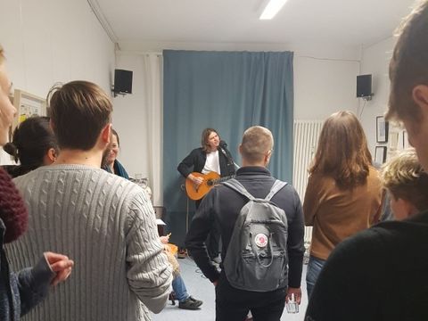 Menschen hören einem singenden Mann mit Gitarre zu