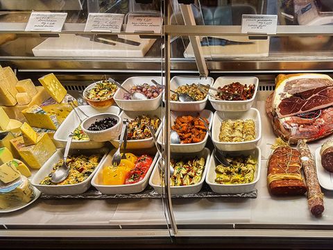 In einer Glastheke befinden sich in mehreren weißen Porzelanschüsseln unterschiedliche italieniesche Antipasti