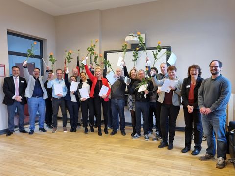 Die Absolventen und Absolventeninenn feiern lachend ihren Erfolg.