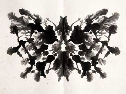 Symmetrischer schwarzer Tintenklecks eines Rorschachtests auf weißem Papier.