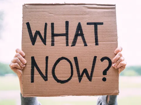 Pappschild mit Aufschrift What Now?