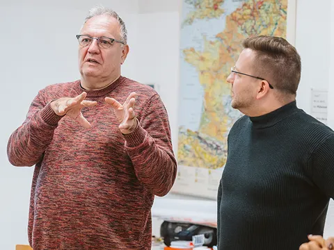 Teilnehmende diskutieren und gestikulieren stehend im Raum