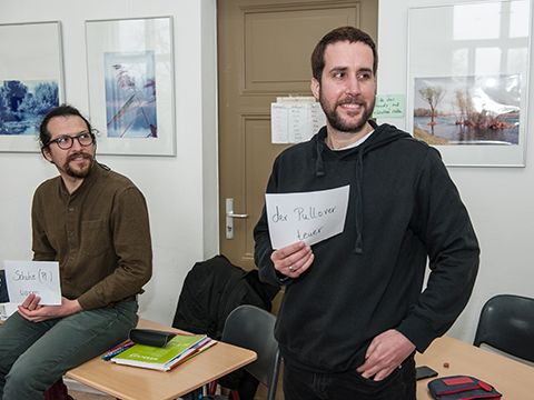 Zwei Männer zeigen ihre Übersetzung auf einem Blatt Papier