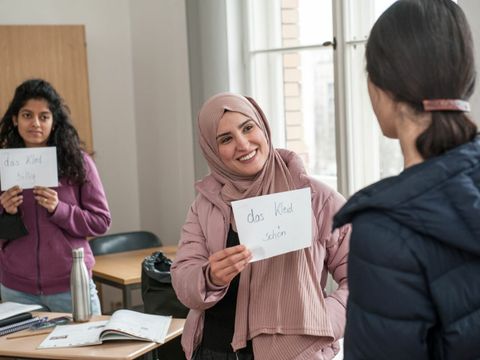 Deutschkurs, Frau zeigt ein beschriftetes Blatt der Kursleiterin