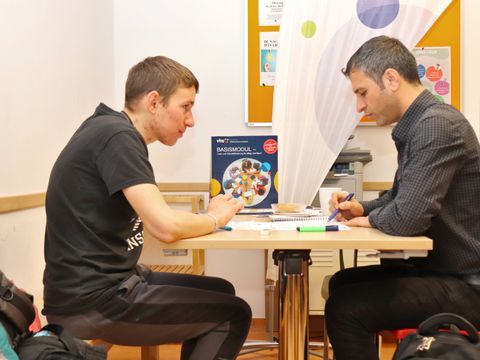 Zwei Personen sitzen am Tisch und lernen.