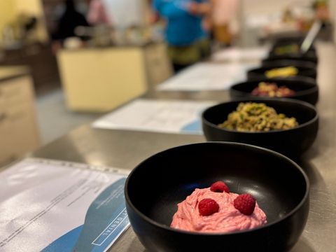 Bunte vegane und vegetarische Brotaufstriche in schwarzen Schüsseln hintereinander aufgereiht mit ausgedruckten Rezepten daneben
