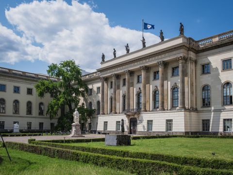 Der Ehrenhof der HU samt verschiedener Denkmäler. Dahinter das HU-Hauptgebäude auf dem die HU-Flagge weht.