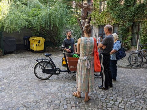 Eine Person erklärt drei weiteren Personen das Lastenrad, das vor ihnen steht