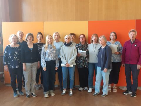 Eine Gruppe von Menschen schaut stehend in die Kamera
