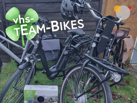 Schwarze Fahrräder mit Aufklebern ‚VHS TEAM-BIKES‘ nebeneinander geparkt