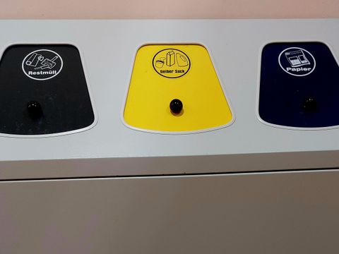 Drei kleine Mülltonnen mit verschiedenfarbigen Deckeln (Schwarz, Gelb, Blau)