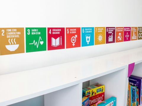 Wand mit Symbolen der 17 Ziele für nachhaltige Entwicklung (SDGs) über einem Regal