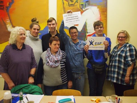 Gruppe von Menschen lächelt in die Kamera, zwei halten Schilder mit ESF-Logo