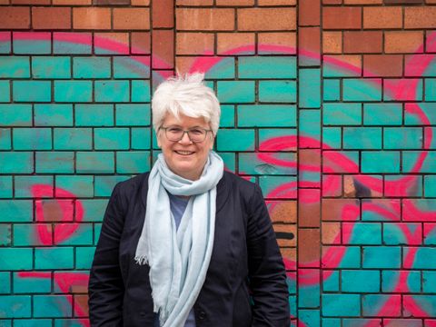 Eine Frau steht vor einer bunten Graffitiwand