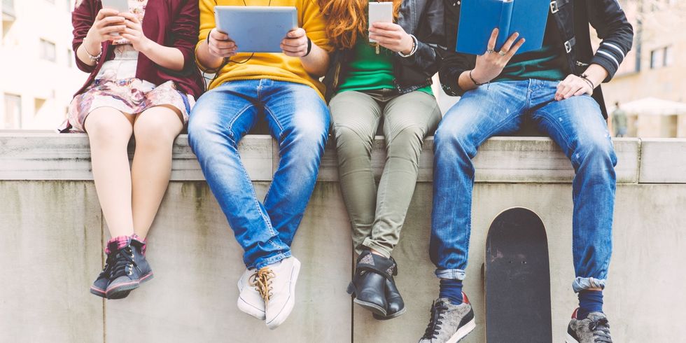 Gruppe von Menschen sitzen mit Buch oder digitalem Gerät zusammen, nur Unterkörper zu sehen