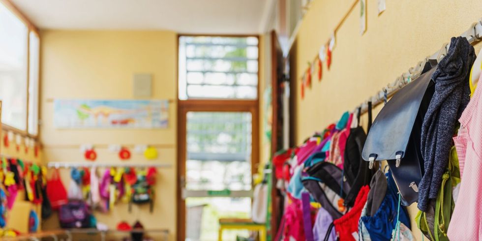 Flur eines Kindergartens mit bunten Rucksäcken und Jacken an Haken und auf Bänken