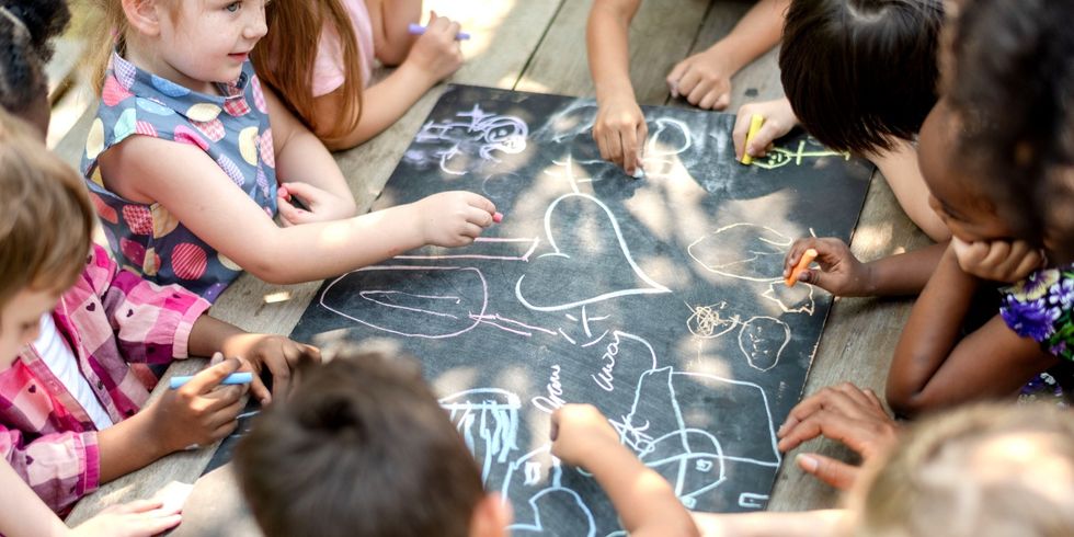 Kinder malen zusammen draußen mit Kreide.