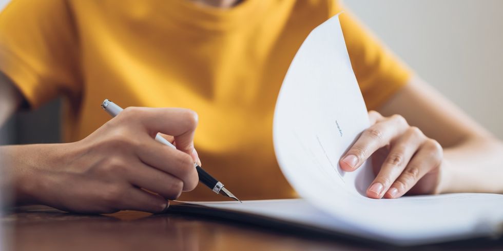 Eine Frau unterzeichnet ein Dokument und hält dabei den Stift in der Hand