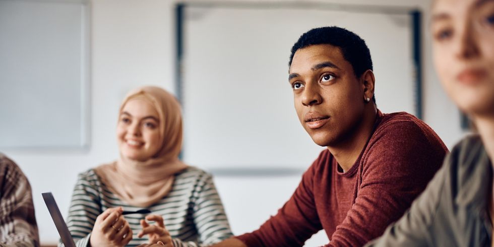 Multiethnische Gruppe Studenten sitzt zuhörend an einem Arbeitstisch