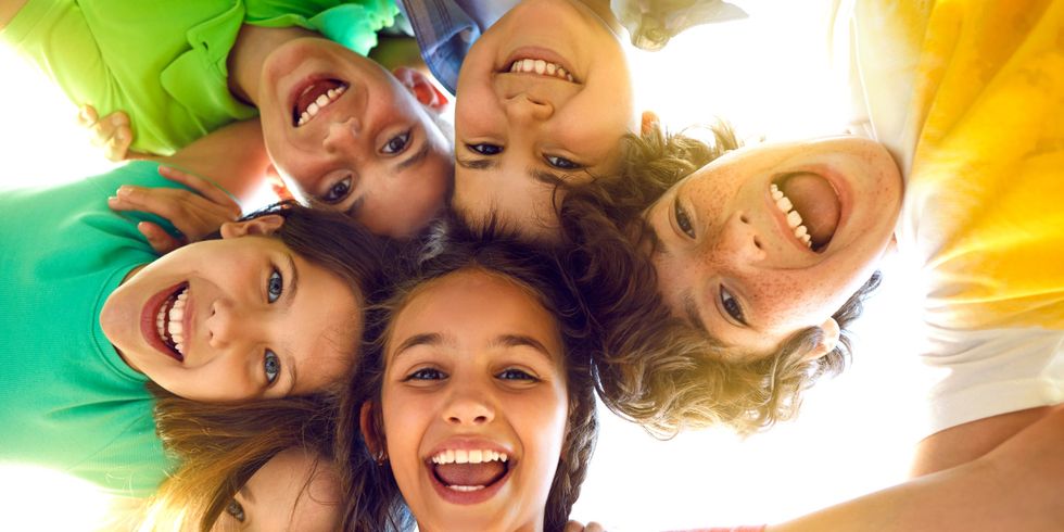 Group of happy little children playing together, having fun, huddling, looking down and smiling