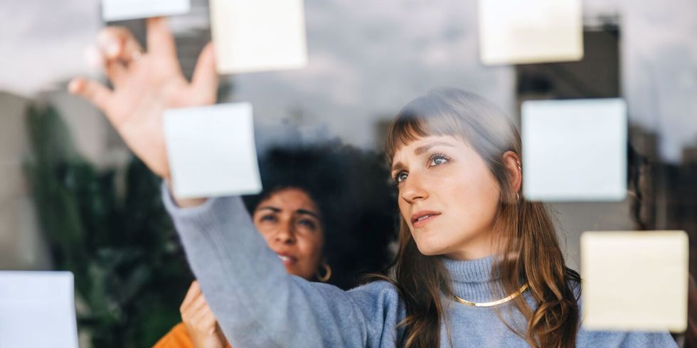 Zwei junge Geschäftsfrauen beim Brainstorming mit Haftnotizen in einem Büro