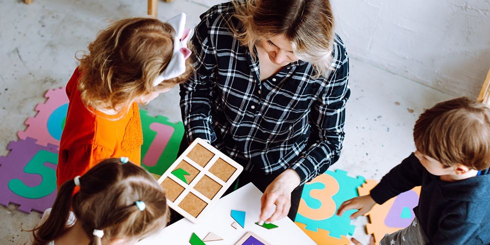 Eine Erzieherin, die gemeinsam mit den Kindern eine Puzzle-Übung durchführt