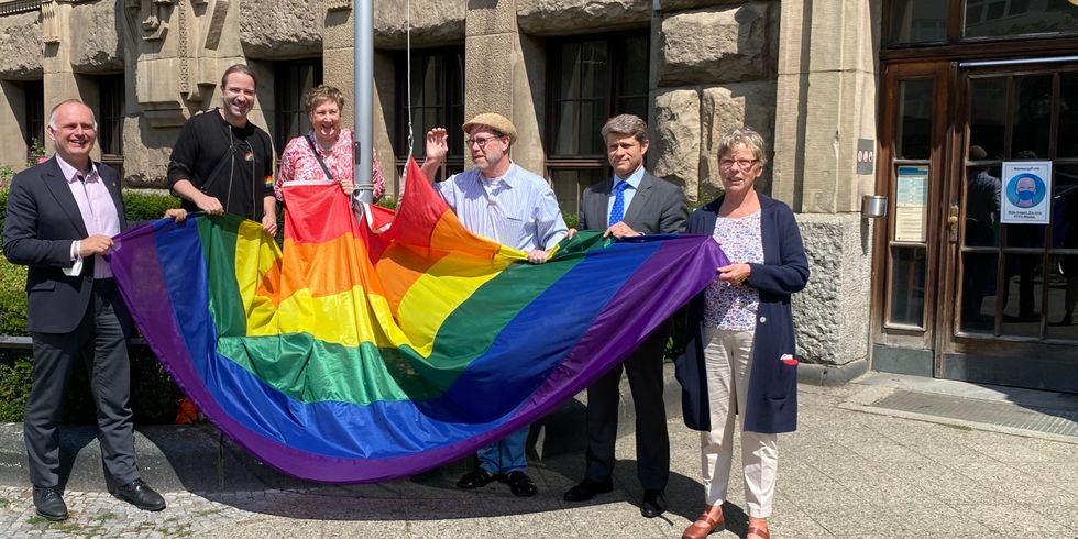 Bezirgsbürgermeister Reinhard Naumann hisst Regenbogeflagge vor Rathaus