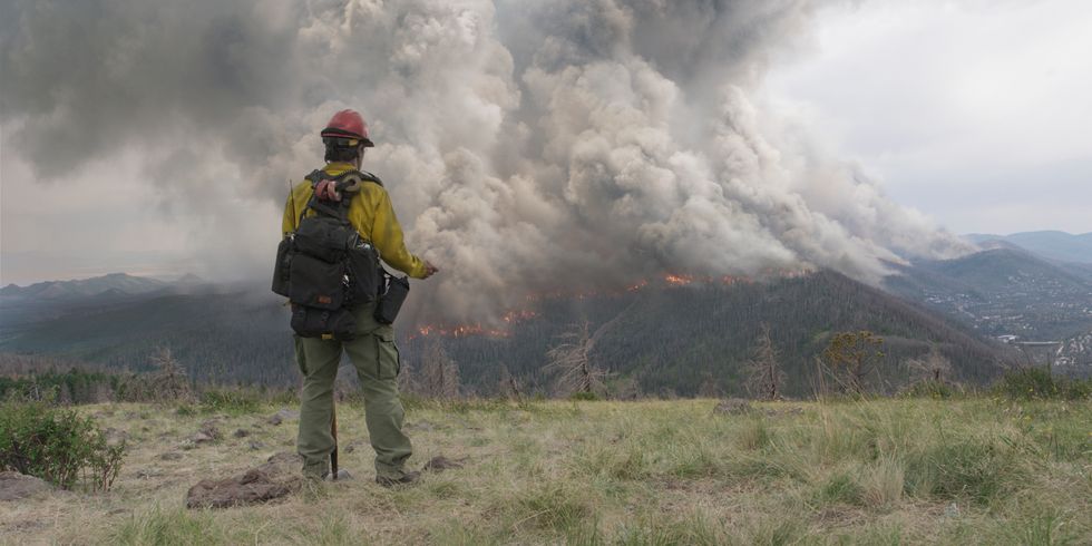 Aus dem Film „No Way Out - gegen die Flammen“ - Feuerwehrmann steht im Gebirge - im Hintergrund brennt Wald