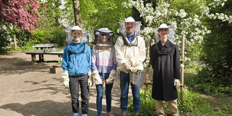 Der Leiter der Umwelt- und Bienen-AG mit teilnehmenden Schüler*innen im Schulgarten